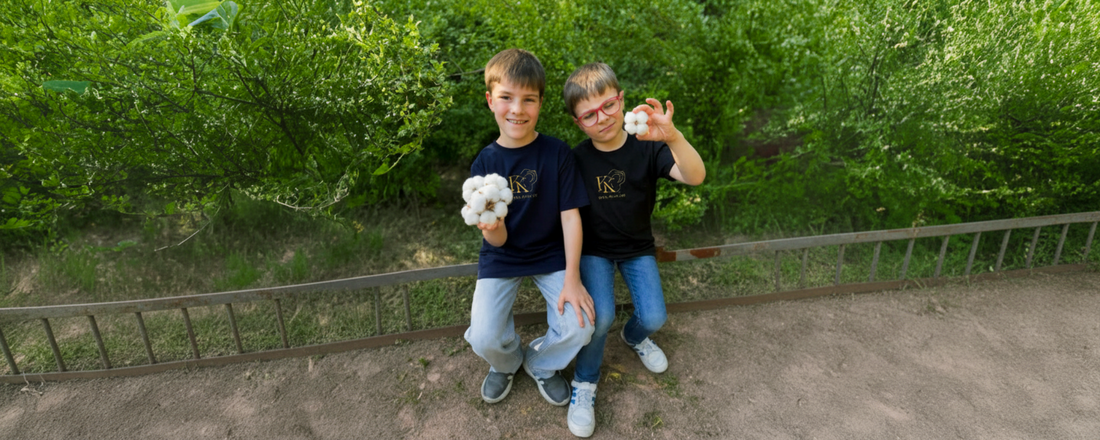 Zwei Kinder in Karl-Kaplan-Shirts halten Bio-Baumwolle im Grünen